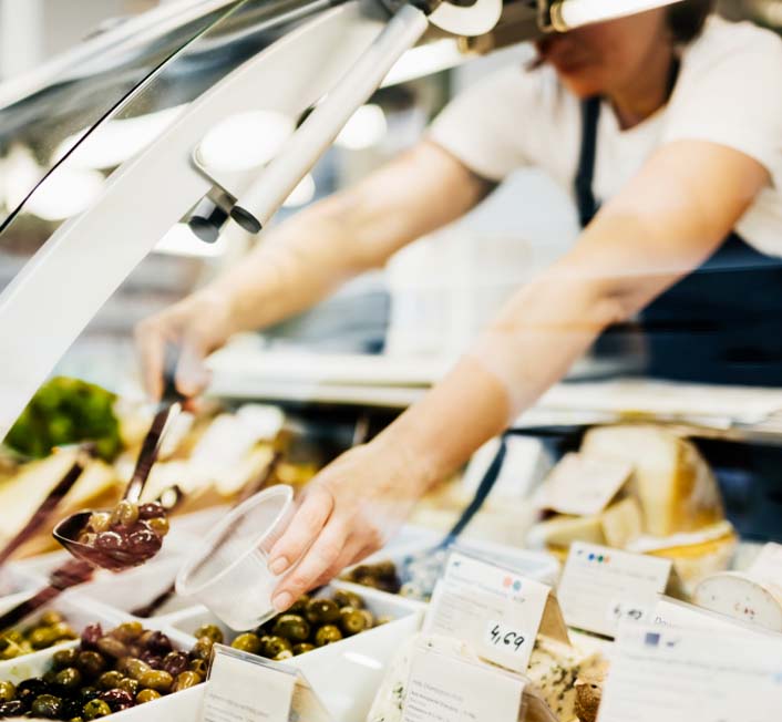 a woman serving food at a deli